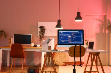 Karanlık ofisin içinde cihazları olan programcının çalışma yeri