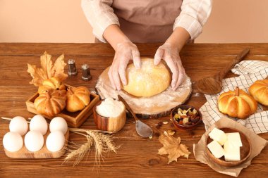 Balkabağı şeklinde çörekler hazırlayan kadın ışık duvarının yanındaki masada.