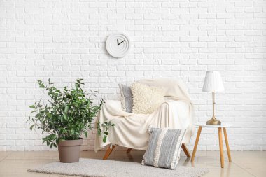 Oturma odasının içinde koltuk, masa lambası ve çiçek var.