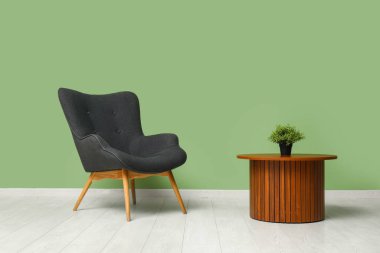 Ahşap masa, bitki ve renkli duvarın yanındaki rahat koltuk.