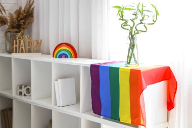 Yatak odasındaki rafta bambu saplı vazo ve LGBT bayrağı