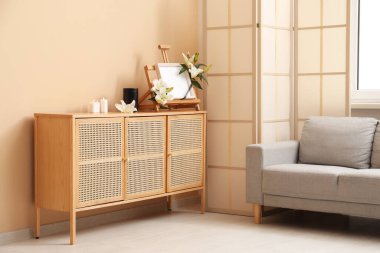 Boş bir cenaze çerçevesi, nilüfer çiçekleri, morg vazosu ve odasındaki ahşap dolapta yanan mumlar.