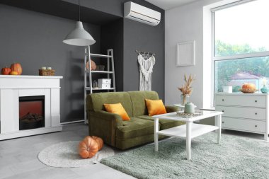 İçinde elektrikli şömine, kanepe ve balkabağı olan oturma odası.