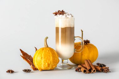 Beyaz arka planda yıldız anason ve tarçınlı bir bardak lezzetli balkabaklı latte.