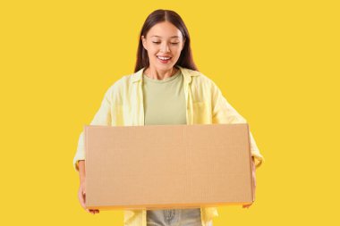 Sarı arka planda paketli genç Asyalı kadın.
