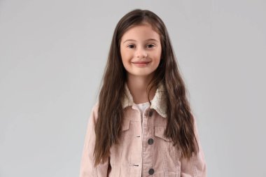 Hafif arka planda, kalın ceketli küçük kız.