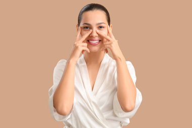 Yüzüne bej arka planda masaj yapan güzel genç bir kadın.