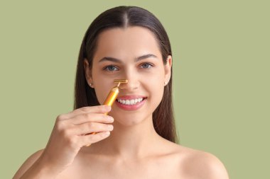 Yüzüne yeşil arka planda bir aletle masaj yapan güzel bir genç kadın.