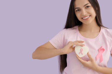 Leylak arka planında kurdele ve kurabiye olan genç bir kadın. Göğüs kanseri farkındalığı konsepti