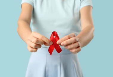 Mavi arka planda kırmızı kurdeleli genç bayan, yakın plan. AIDS konsepti