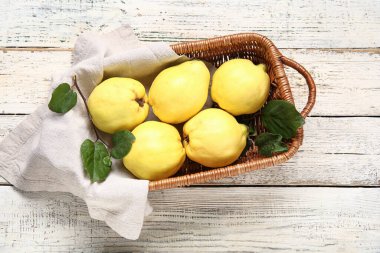 Tatlı olgun bıldırcınlar ve beyaz ahşap arka planda yapraklarla dolu bir sepet.