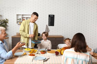 Şükran Günü 'nde mutlu bir aile şenlik masasında yemek yiyor.