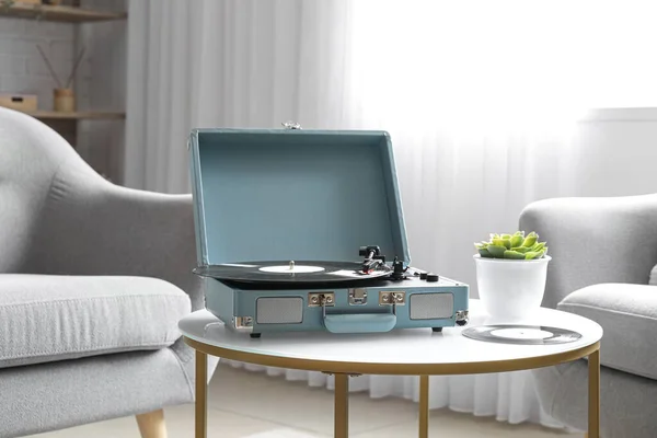 Record player with vinyl disk on table in living room