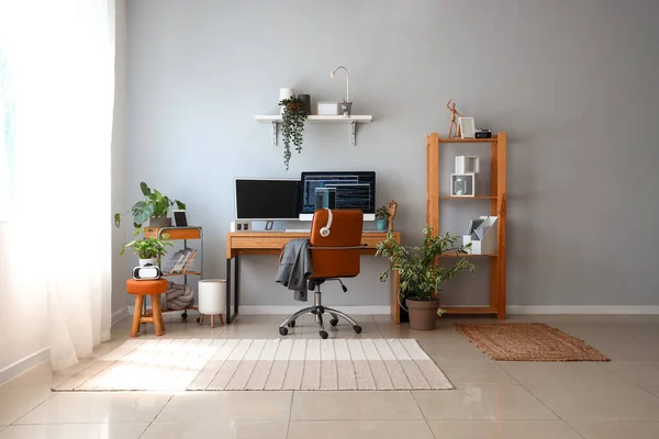 Interior of light office with programmer\'s workplace and houseplants