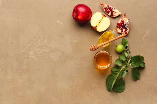 Jar and gravy boat of honey and apples for Rosh Hashanah celebration (Jewish New Year) on brown background