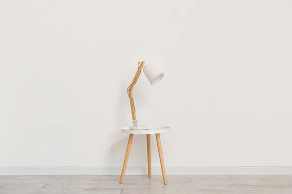 Desk lamp on small table near white wall