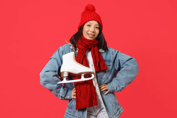 赤い背景にアイススケートと冬の服の若いアジアの女性 — ストック写真