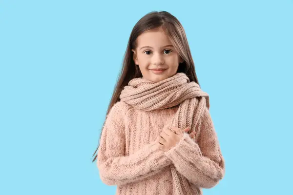 青い背景にスカーフと暖かいセーターの小さな女の子 — ストック写真