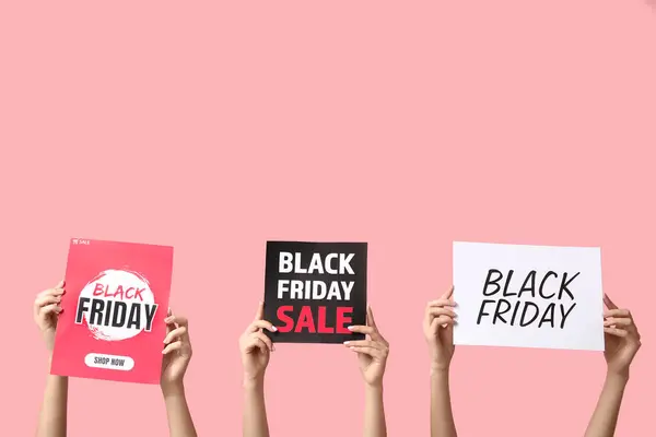 Female hands holding posters with text BLACK FRIDAY SALE on pink background