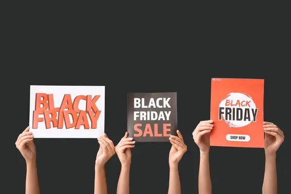 Female hands holding posters with text BLACK FRIDAY on dark background