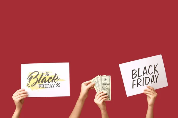 Female hands holding posters with text BLACK FRIDAY and money on red background