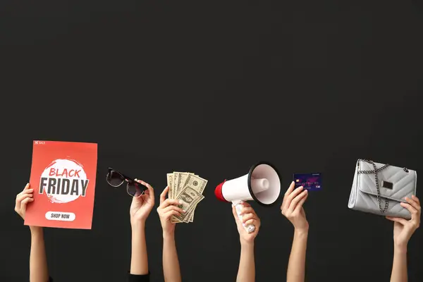 Female hands holding poster with text BLACK FRIDAY, women accessories, money, credit card and megaphone on dark background