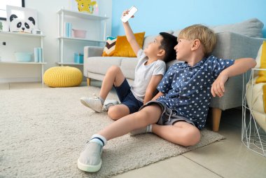 Cep telefonlu şirin çocuklar evde selfie çekiyorlar.