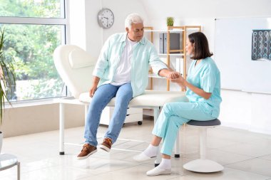 Rehabilitasyon merkezinde kıdemli bir hastayla çalışan kadın fizyoterapist.