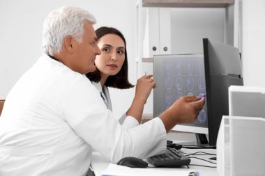 Doktorlar sağlık ofisindeki bilgisayarda röntgen görüntülerini tartışıyor.