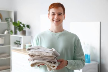 Evde temiz havluları olan genç bir adam.