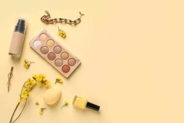 Makyaj ürünleri, güzel jigolo çiçekleri ve bej arka planda bilezik.