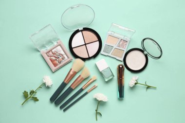 Makyaj ürünleri ve turkuaz arka planda güzel kasımpatı çiçekleri olan kompozisyon