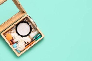 Tahta kutu, makyaj ürünleri ve turkuaz arka planda güzel kasımpatı çiçekleri.