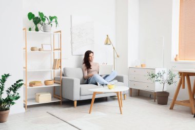 Evde doktorla görüntülü konuşma yapan genç bir kadın.