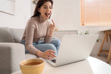 Evde doktorla görüntülü konuşma yapan genç bir kadın var.