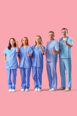 Pembe arka planda kırmızı kurdeleli profesyonel doktor ekibi. Dünya AIDS Günü konsepti