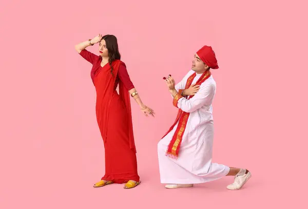 Young Indian woman rejecting marriage proposal on pink background