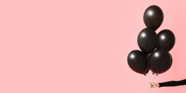 Pembe arka planda balonlar ve mesaj için yer olan bir el. Kara Cuma indirimi