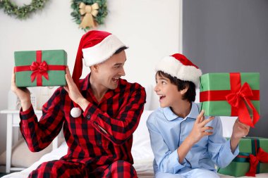 Babasıyla küçük bir çocuk ve Noel hediyeleri yatak odasında.