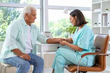 Rehabilitasyon merkezinde kıdemli bir hastayla çalışan kadın fizyoterapist.