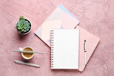 Kalemli defterler ve pembe arka planda bir fincan lezzetli kahve.