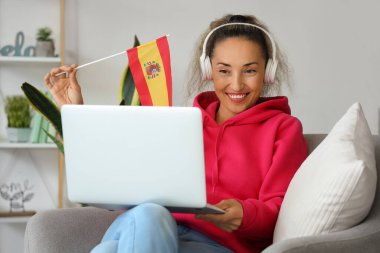 Mature woman with laptop studying Spanish online at home clipart