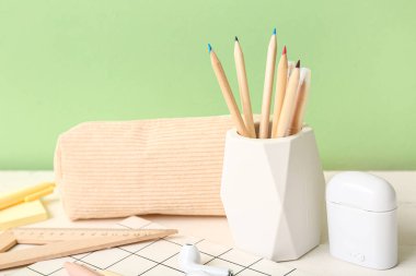 Farklı kırtasiye malzemeleri ve hafif ahşap masada modern kulaklıkları olan Holder, yakın plan.