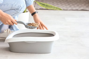 Evde kedi için bir kepçe tahta çöpü olan kadın, yakın plan.