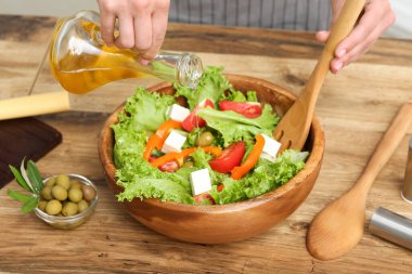 Kadın tabağa zeytinyağı ve lezzetli salata ekliyor.