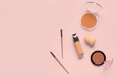 Bir şişe makyaj vakfı ve pembe arka planda dekoratif kozmetik ürünleri.