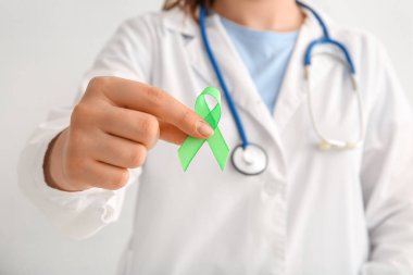 Yeşil Farkındalık Kurdelesi tutan kadın doktor, yakın plan. Ruh Sağlığı Günü