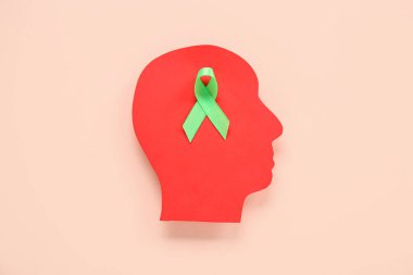 Pembe arka planda yeşil farkındalık kurdelesi olan kağıt insan kafası. Ruh Sağlığı Günü