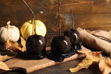 Cadılar Bayramı için karamelli elmalar ve ahşap arka planda sonbahar yaprakları.