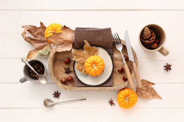 Beyaz ahşap zemin üzerinde balkabakları, kestaneler ve kuru yapraklar ile sonbahar masa ayarı